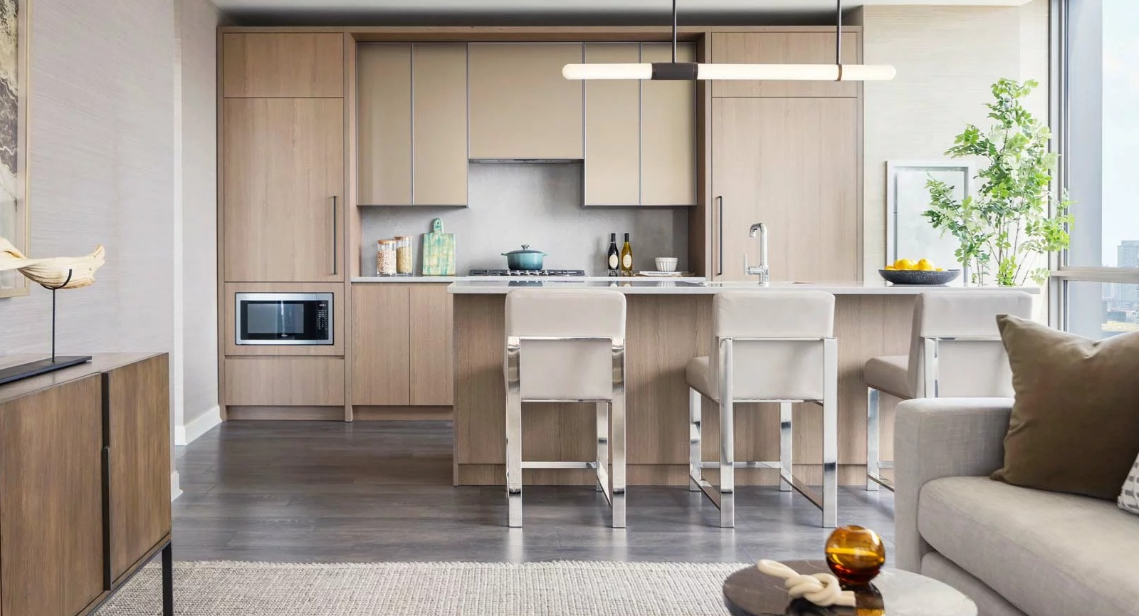 Spacious open-concept kitchen and living room at The Row Fulton Market in Chicago, featuring light wood cabinets, an island, and modern furniture