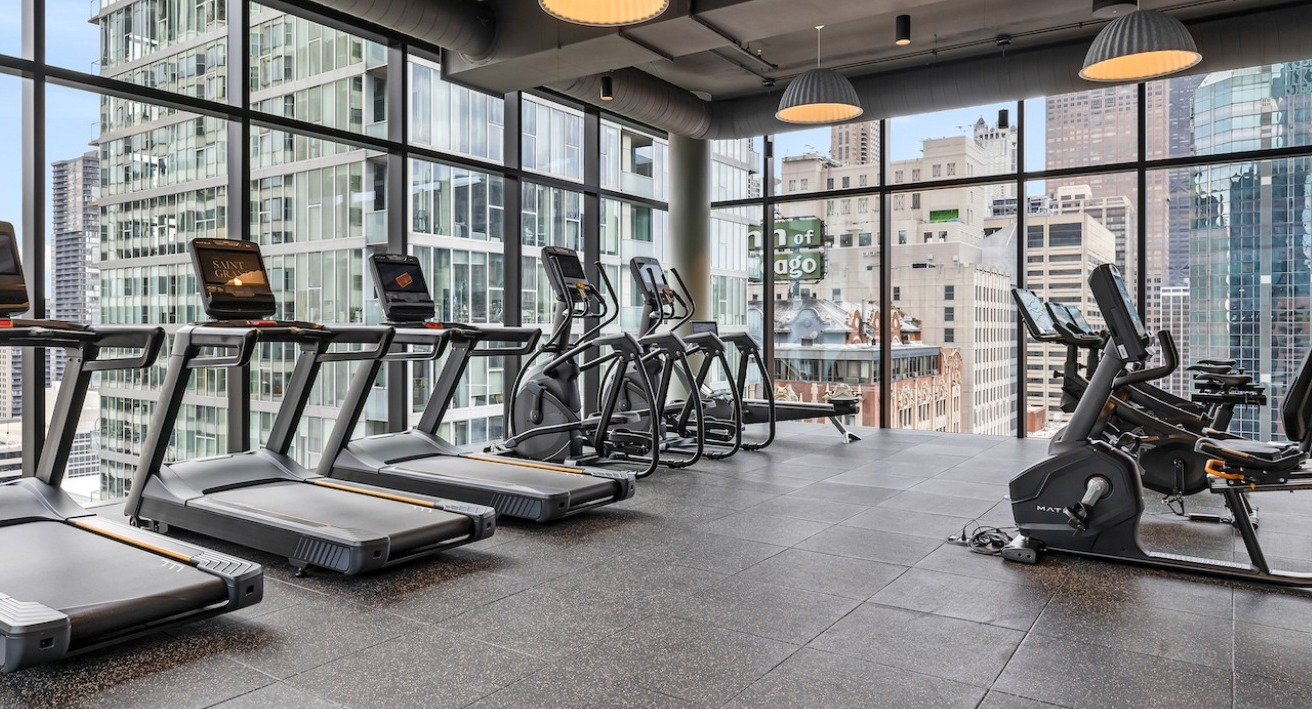 State-of-the-art cardio gym at The Saint Grand in Chicago, featuring treadmills, ellipticals, and stunning city skyline views