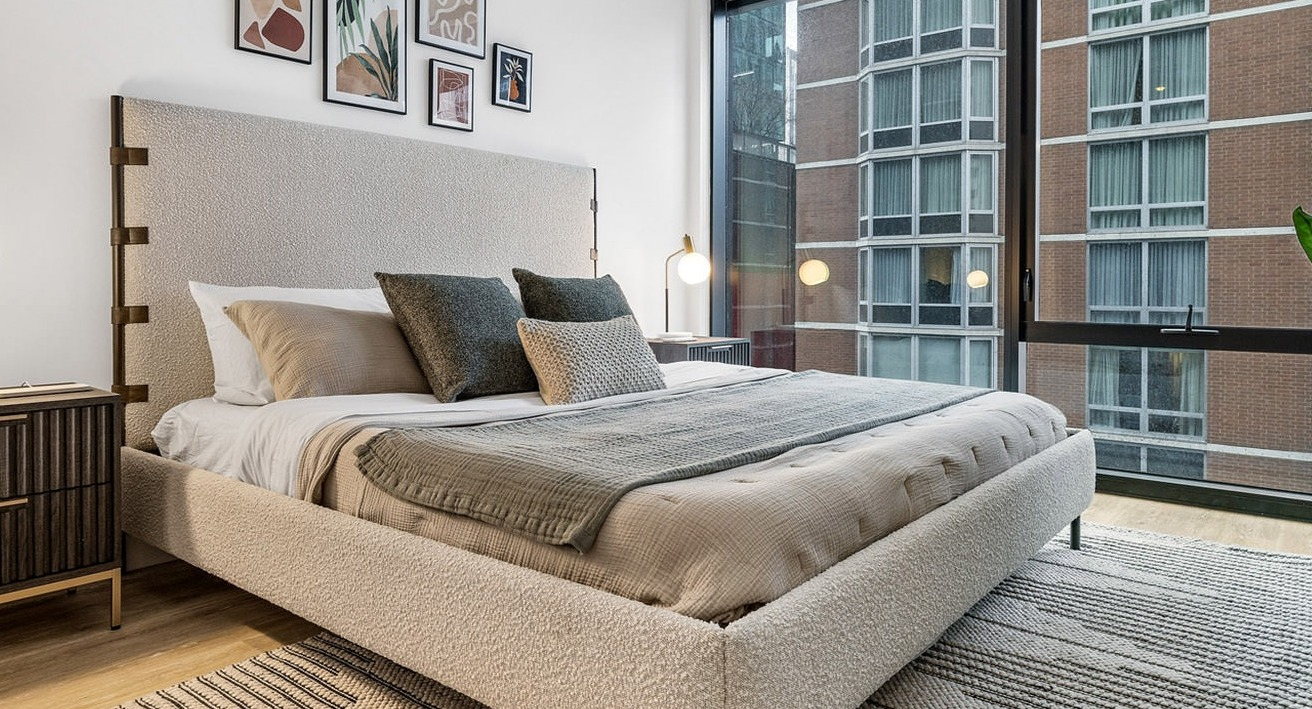 Cozy bedroom at The Saint Grand in Chicago, featuring a comfortable bed, warm lighting, and large windows with urban views