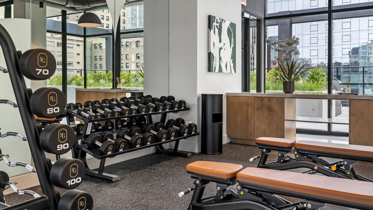 Modern fitness center at The Saint Grand in Chicago, featuring a wide selection of free weights, benches, and ample workout space
