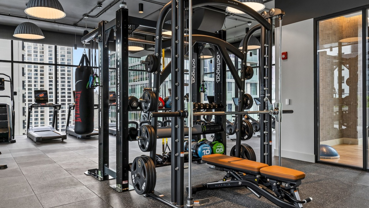 Advanced gym at The Saint Grand in Chicago, featuring comprehensive strength training equipment, free weights, and city views