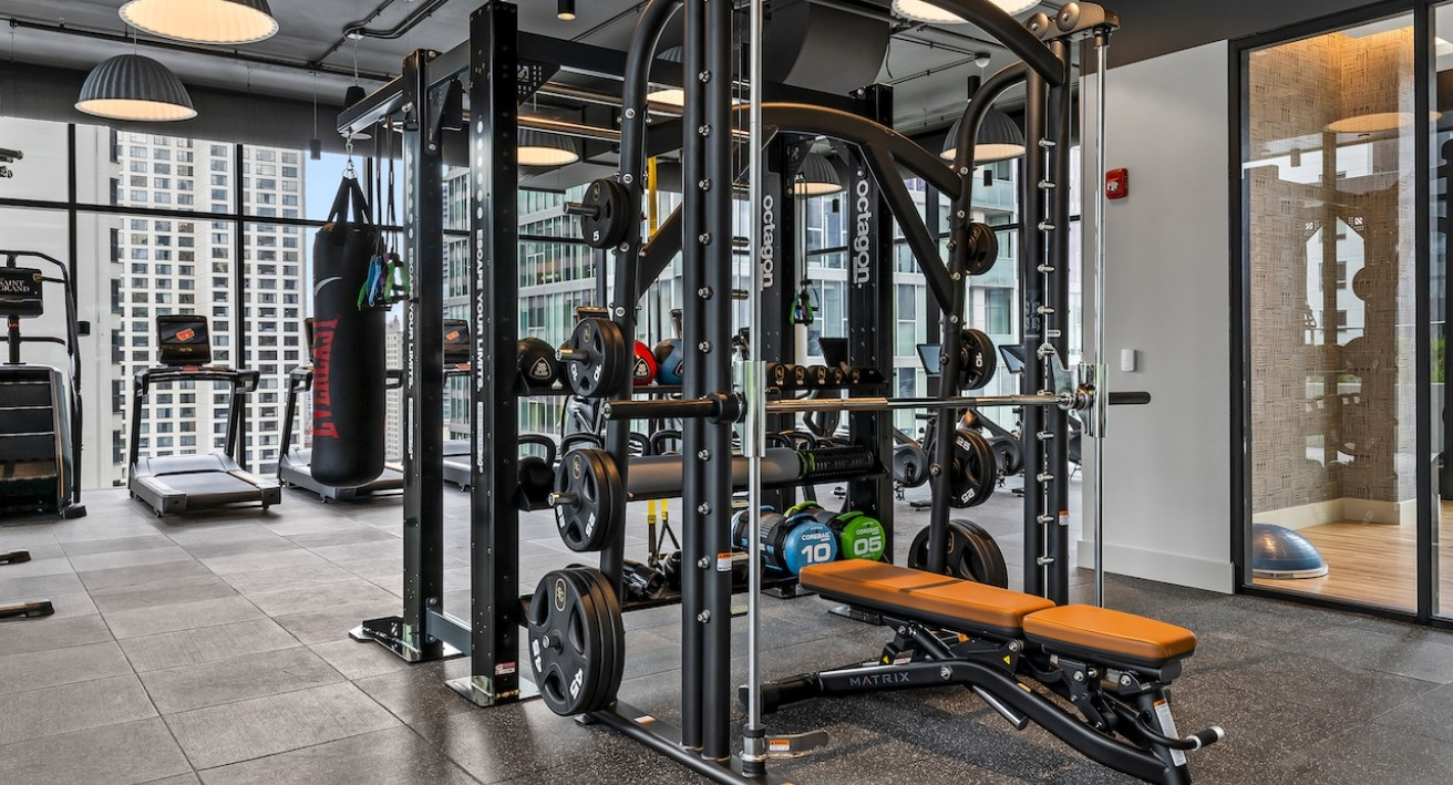 Advanced gym at The Saint Grand in Chicago, featuring comprehensive strength training equipment, free weights, and city views