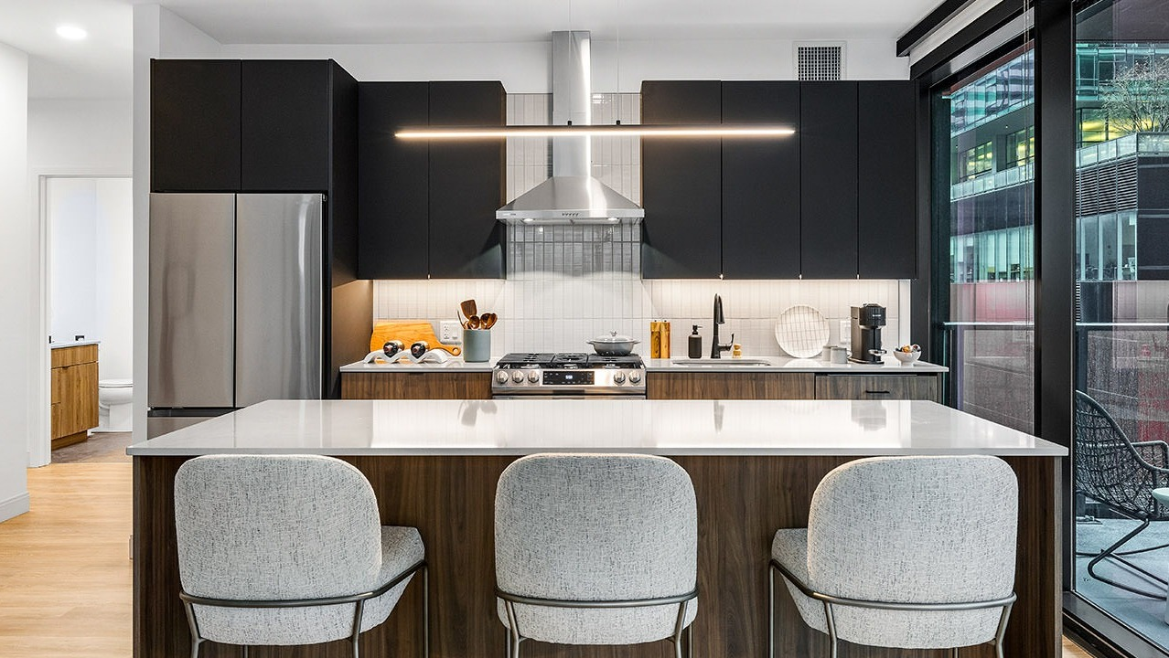 Modern kitchen at The Saint Grand in Chicago, featuring an island, sleek black cabinetry, stainless steel appliances, and a balcony