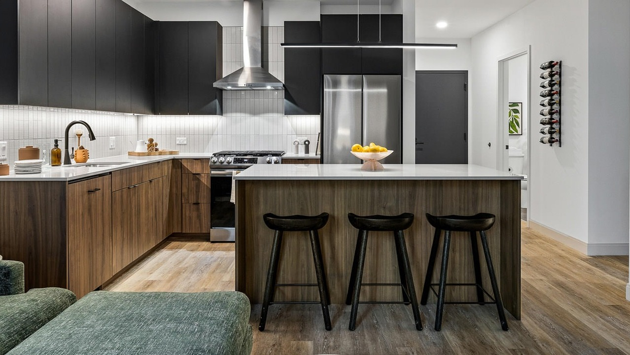 Modern apartment kitchen at The Saint Grand in Chicago, featuring a spacious island with seating, dark cabinetry, and sleek finishes