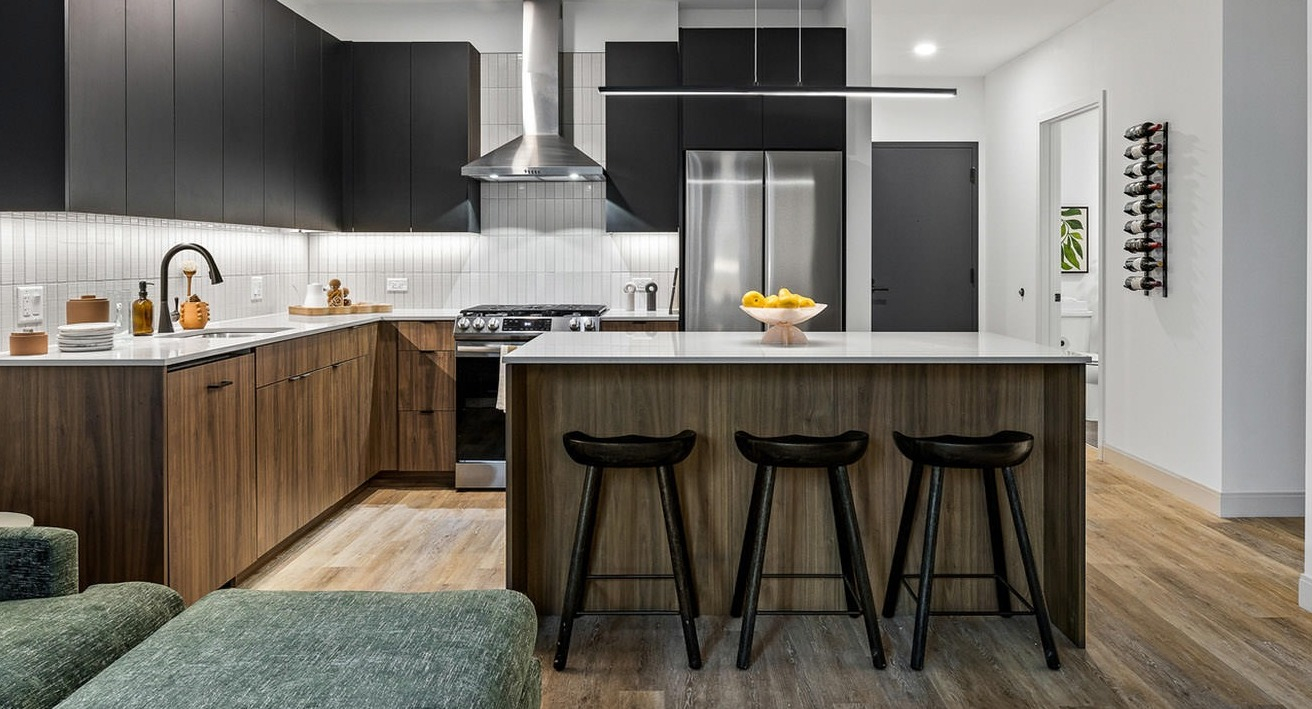 Modern apartment kitchen at The Saint Grand in Chicago, featuring a spacious island with seating, dark cabinetry, and sleek finishes
