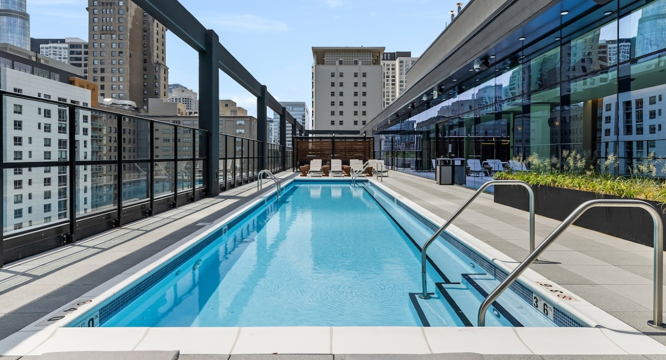 Serene rooftop pool deck at The Saint Grand in Chicago, featuring a long swimming pool, lounge areas, and panoramic city views