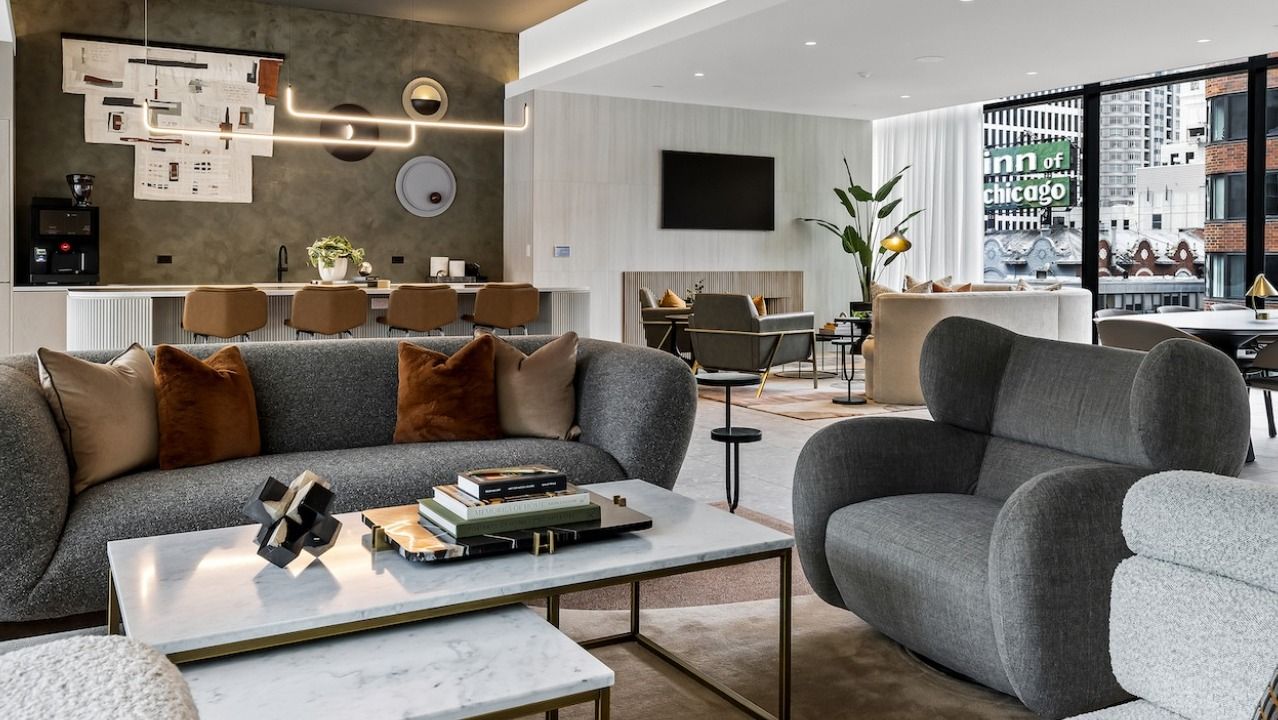 Modern resident lounge at The Saint Grand in Chicago, featuring multiple seating areas, a full kitchen, and stylish decor
