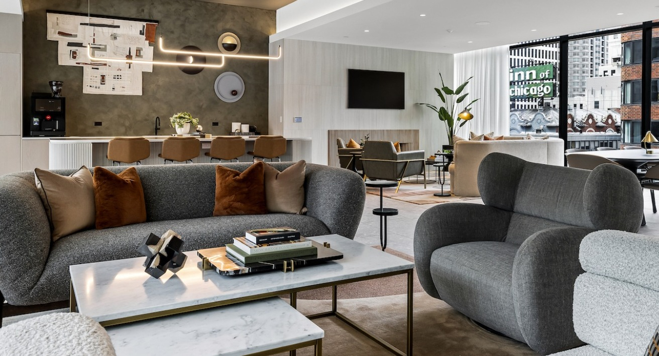 Modern resident lounge at The Saint Grand in Chicago, featuring multiple seating areas, a full kitchen, and stylish decor