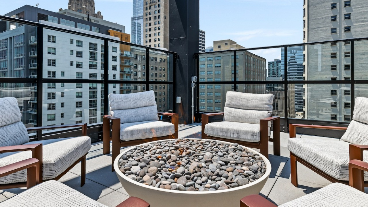 Inviting rooftop fire pit lounge at The Saint Grand in Chicago, featuring comfortable seating and a stunning city backdrop
