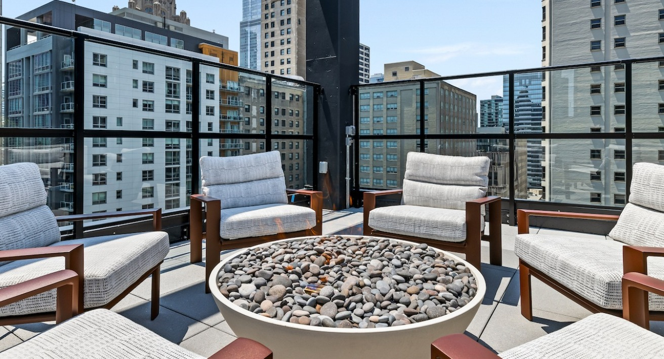 Inviting rooftop fire pit lounge at The Saint Grand in Chicago, featuring comfortable seating and a stunning city backdrop