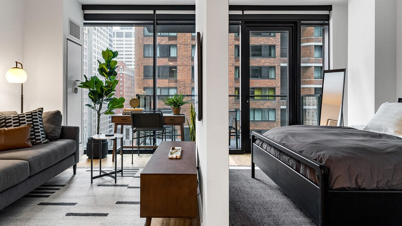 Thoughtfully designed studio apartment with distinct living and sleeping areas, modern furniture, and large windows at The Saint Grand in Chicago