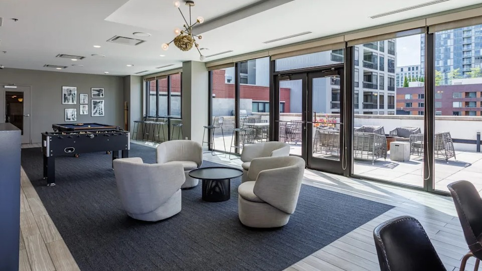 Elegant clubroom lounge with plush armchairs, stylish decor, and access to an outdoor patio at The Scott Residences in Chicago