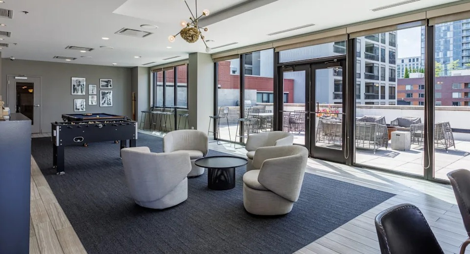 Elegant clubroom lounge with plush armchairs, stylish decor, and access to an outdoor patio at The Scott Residences in Chicago