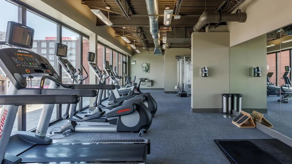 Well-equipped fitness center with various cardio machines including treadmills, ellipticals, and a full-length mirror wall at The Scott Residences in Chicago
