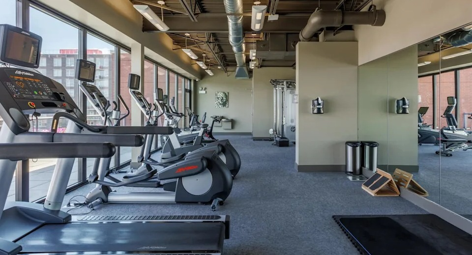 Well-equipped fitness center with various cardio machines including treadmills, ellipticals, and a full-length mirror wall at The Scott Residences in Chicago