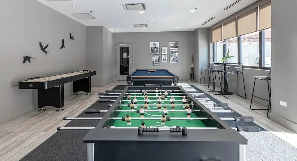 Vibrant game room featuring shuffleboard, foosball, and a billiards table, perfect for entertainment at The Scott Residences in Chicago