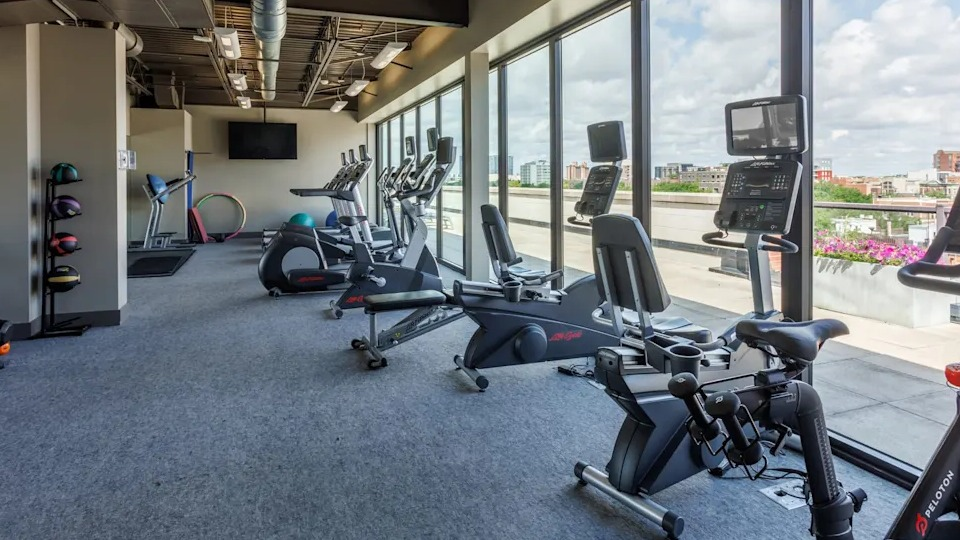 Dynamic gym space featuring exercise bikes, treadmills, and free weights, all with large windows for natural light at The Scott Residences in Chicago