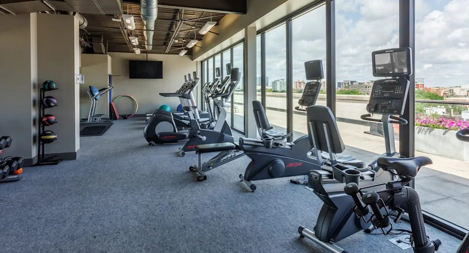 Dynamic gym space featuring exercise bikes, treadmills, and free weights, all with large windows for natural light at The Scott Residences in Chicago