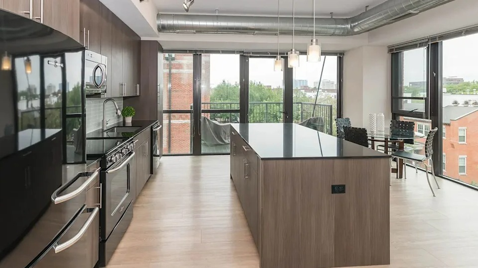 Expansive kitchen and dining area with modern appliances, a large island, and access to a private balcony at The Scott Residences in Chicago