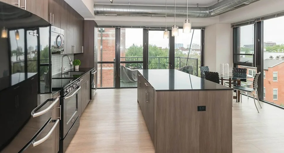 Expansive kitchen and dining area with modern appliances, a large island, and access to a private balcony at The Scott Residences in Chicago