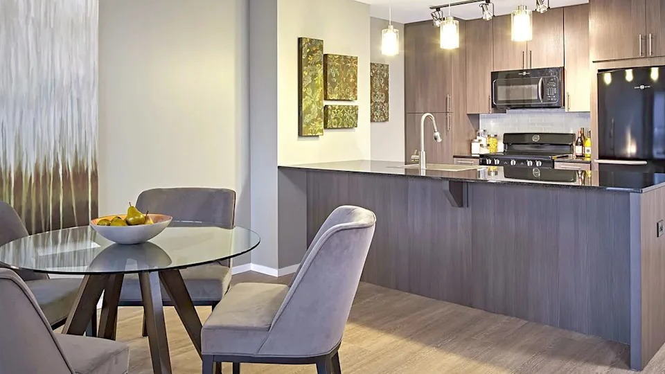 Contemporary kitchen and dining area with dark wood cabinets, a spacious island, and an elegant dining table at The Scott Residences in Chicago