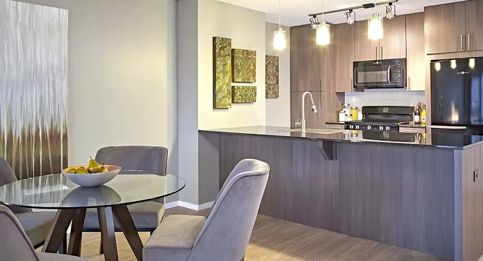 Contemporary kitchen and dining area with dark wood cabinets, a spacious island, and an elegant dining table at The Scott Residences in Chicago
