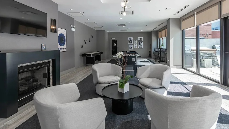 Inviting resident lounge with a modern fireplace, comfortable seating, and a view into the game room at The Scott Residences in Chicago
