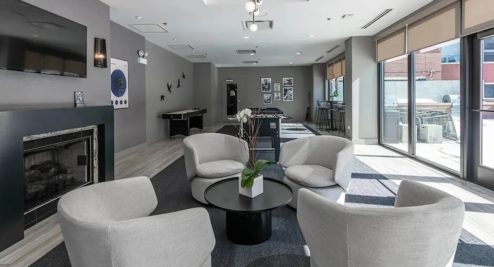 Inviting resident lounge with a modern fireplace, comfortable seating, and a view into the game room at The Scott Residences in Chicago