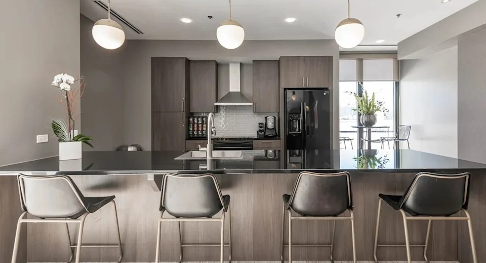 Modern resident kitchen with a large island and bar seating, perfect for communal cooking and entertaining at The Scott Residences in Chicago