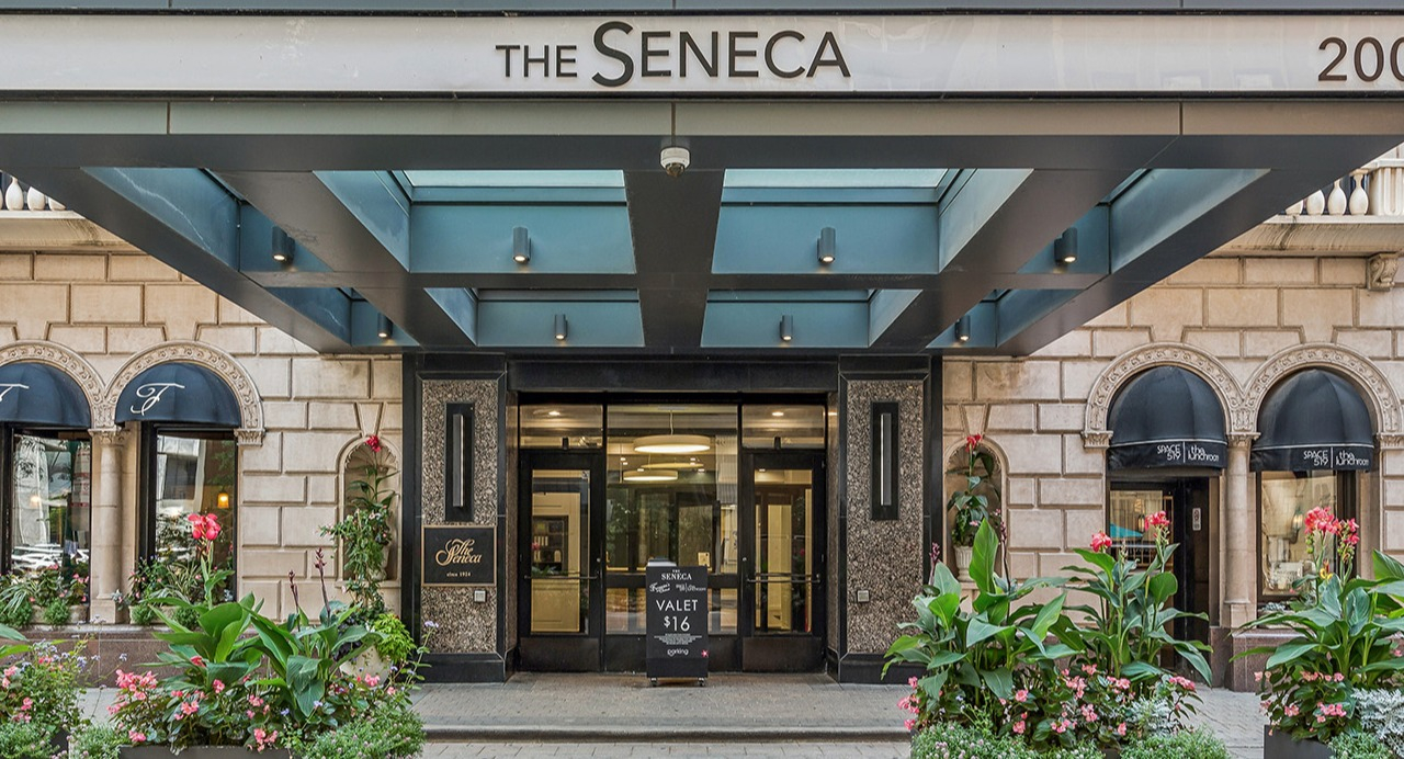 Grand building entrance of The Seneca Apartments in Chicago, featuring elegant architecture, lush planters, and clear signage