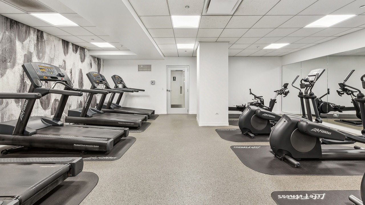 Modern cardio fitness center at The Seneca Apartments in Chicago, featuring treadmills, ellipticals, and a mirrored wall