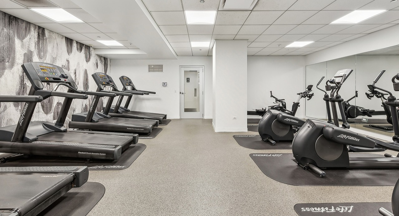 Modern cardio fitness center at The Seneca Apartments in Chicago, featuring treadmills, ellipticals, and a mirrored wall