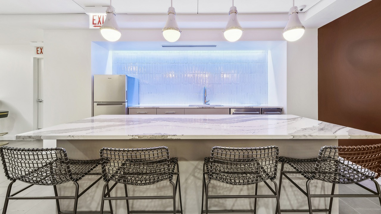 Modern communal kitchen at The Seneca Apartments in Chicago, featuring a large island with seating, pendant lights, and stainless steel appliances