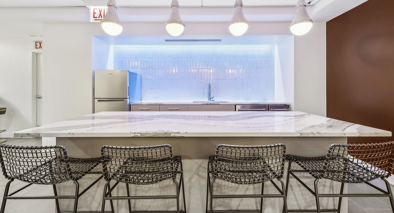 Modern communal kitchen at The Seneca Apartments in Chicago, featuring a large island with seating, pendant lights, and stainless steel appliances