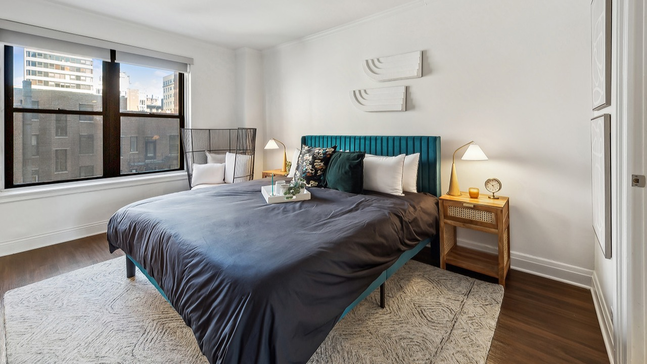 Cozy bedroom at The Seneca Apartments in Chicago, featuring a comfortable bed, large window, and stylish bedside tables