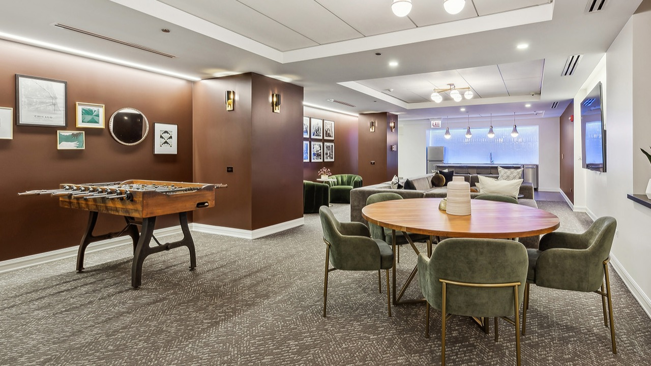 Vibrant game room and lounge at The Seneca Apartments in Chicago, featuring a foosball table, comfortable seating, and modern decor