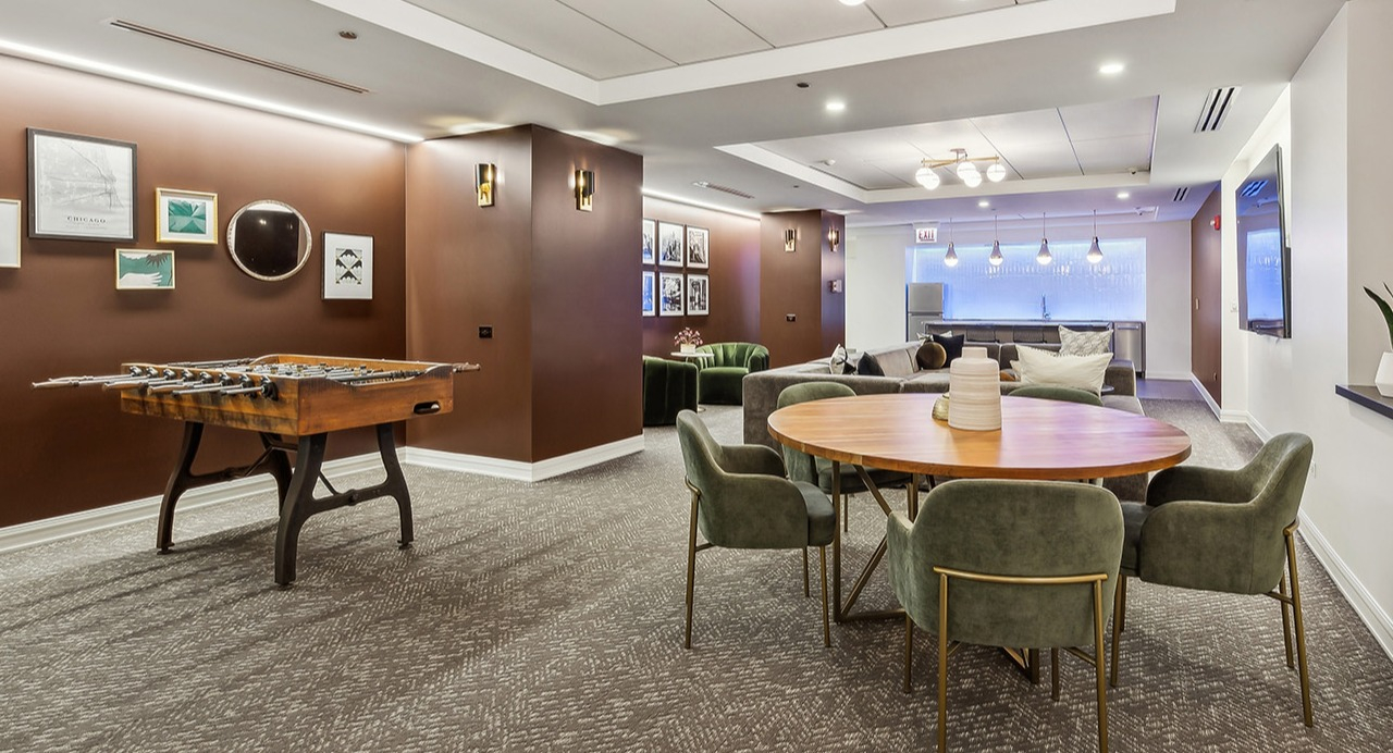 Vibrant game room and lounge at The Seneca Apartments in Chicago, featuring a foosball table, comfortable seating, and modern decor