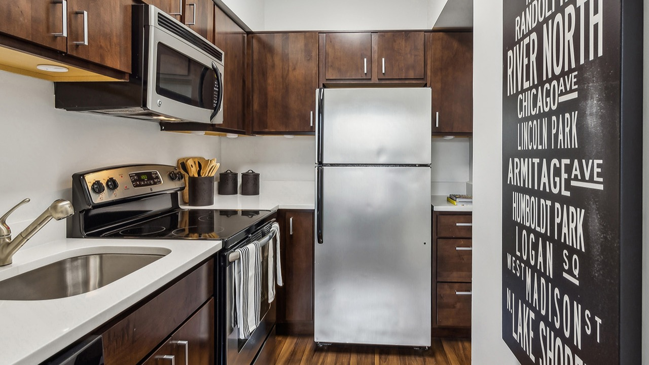 Modern apartment kitchen at The Seneca Apartments in Chicago, featuring wooden cabinetry, stainless steel appliances, and subway tile backsplash