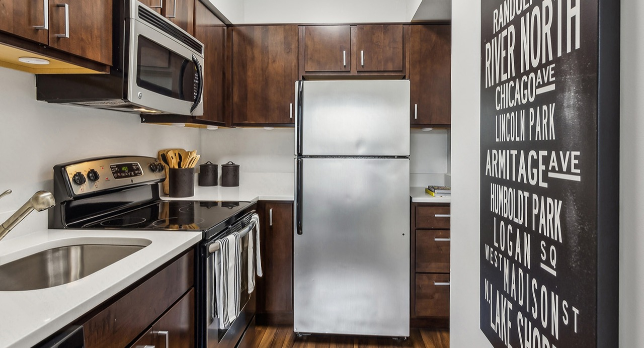 Modern apartment kitchen at The Seneca Apartments in Chicago, featuring wooden cabinetry, stainless steel appliances, and subway tile backsplash