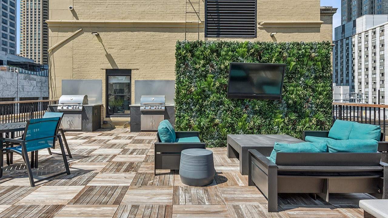 Outdoor rooftop lounge at The Seneca Apartments in Chicago, featuring grilling stations, comfortable seating, and a vertical garden