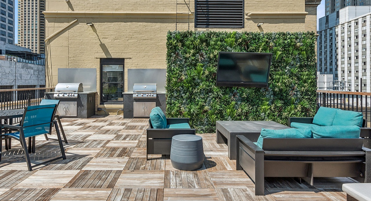Outdoor rooftop lounge at The Seneca Apartments in Chicago, featuring grilling stations, comfortable seating, and a vertical garden