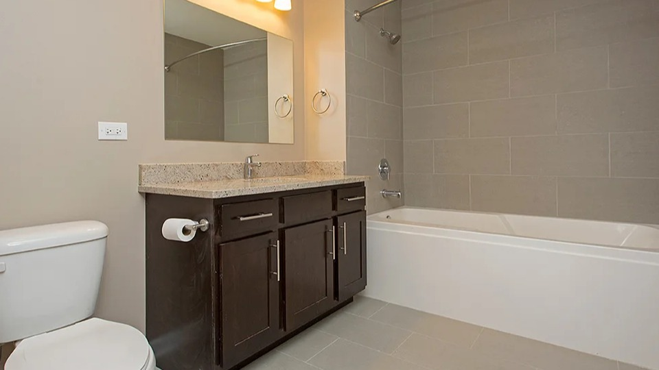 Full bathroom at The Shelby in Chicago, featuring a modern vanity, a combination tub and shower, and neutral tiling