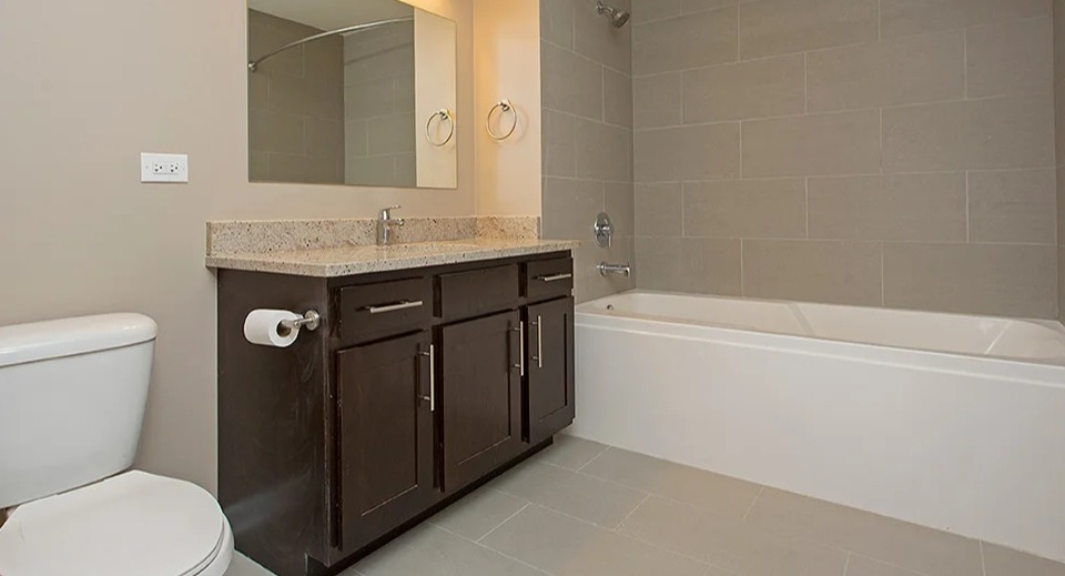 Full bathroom at The Shelby in Chicago, featuring a modern vanity, a combination tub and shower, and neutral tiling