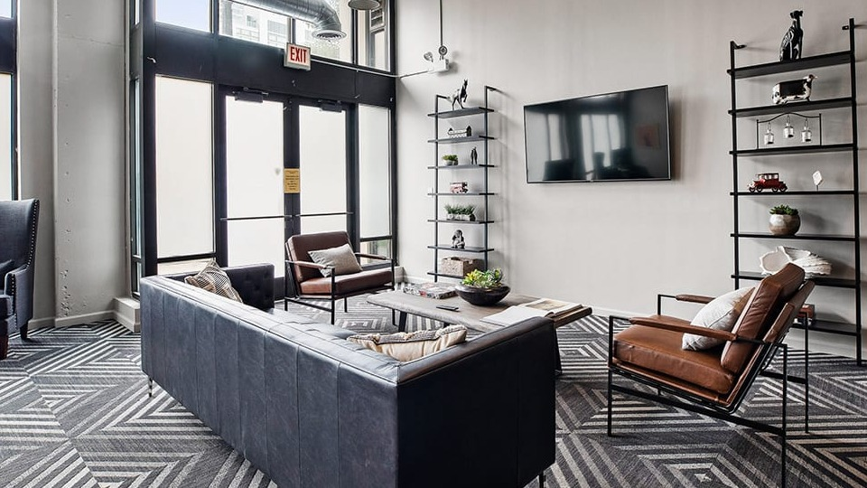 Spacious clubroom lounge area at The Shelby in Chicago, featuring comfortable seating, a large TV, and geometric patterned carpet