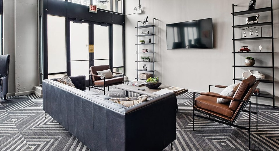 Spacious clubroom lounge area at The Shelby in Chicago, featuring comfortable seating, a large TV, and geometric patterned carpet