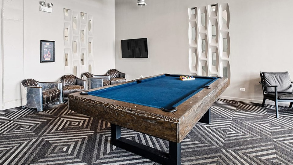 Exciting game room at The Shelby in Chicago, featuring a pool table, comfortable seating, and industrial-chic design elements