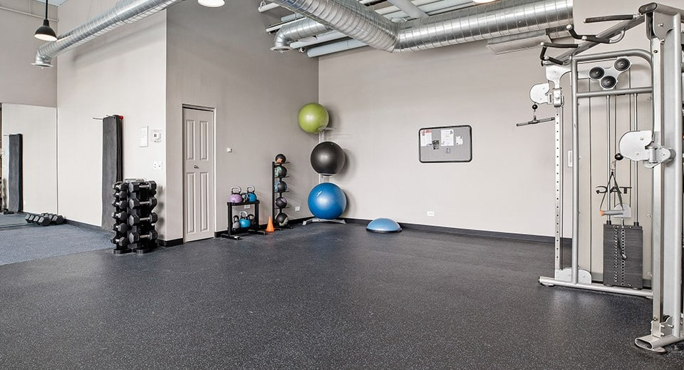 Well-equipped gym at The Shelby in Chicago, featuring a cable machine, free weights, and ample space for various workouts