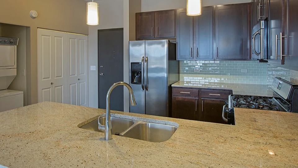 Spacious kitchen at The Shelby in Chicago, featuring a large island, stainless steel appliances, and an in-unit laundry closet