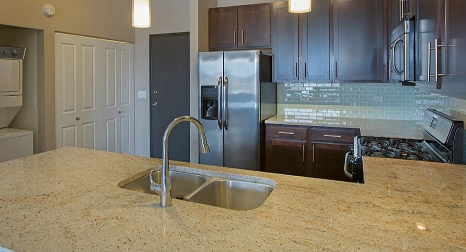 Spacious kitchen at The Shelby in Chicago, featuring a large island, stainless steel appliances, and an in-unit laundry closet