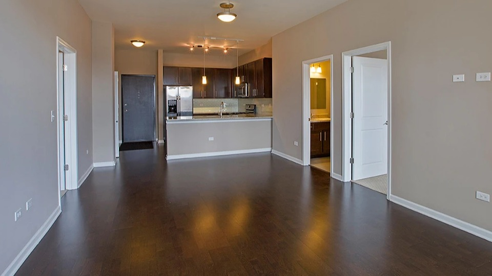 Spacious living room at The Shelby in Chicago, featuring hardwood floors and an open view into the modern kitchen area
